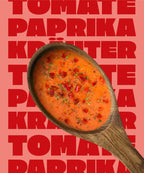Ein Holzlöffel in dem Miss Mineva's fermentierte Suppe mit Geschmacksrichtung Erbse-Kokos-Minze vor einem bunten Hintergrund zu sehen ist