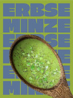Ein Holzlöffel in dem Miss Mineva's fermentierte Suppe mit Geschmacksrichtung Erbse-Kokos-Minze vor einem bunten Hintergrund zu sehen ist